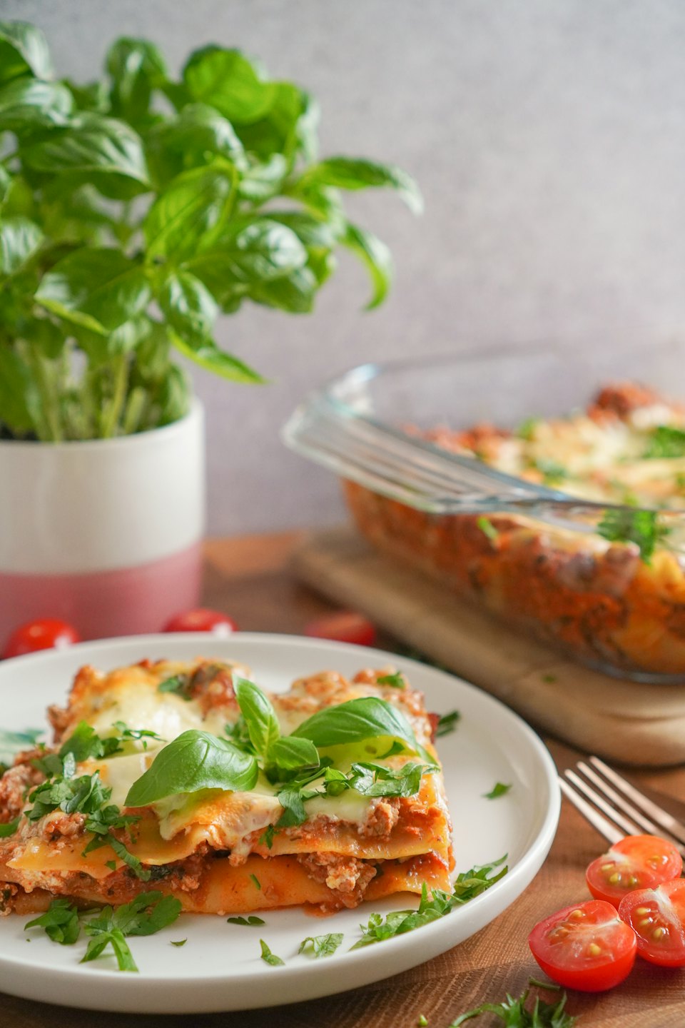 Portion de lasagnes maison avec basilic et persil sur bois.