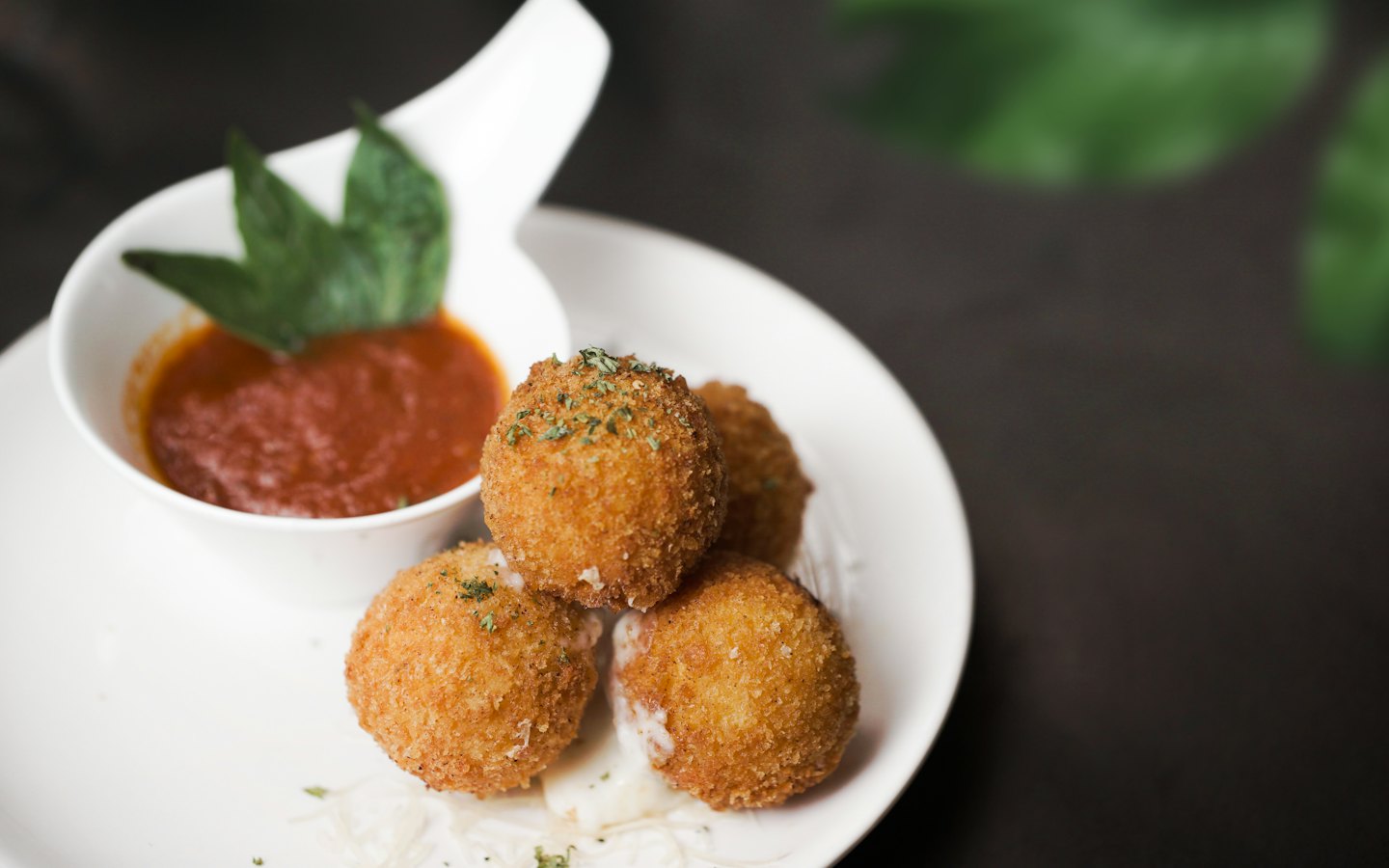 Arancini frits servis avec une sauce rouge dans une assiette.